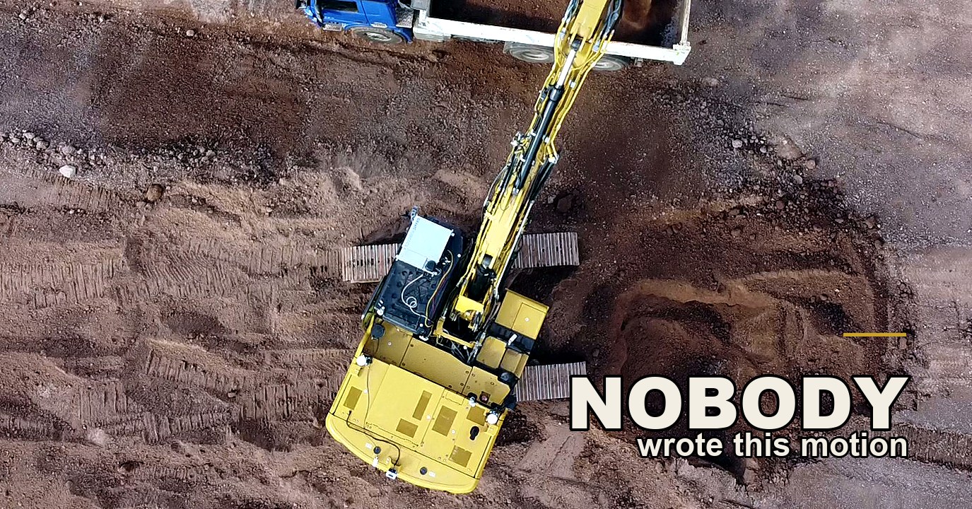 Overhead drone view of a yellow excavator with no operator cab, a black electronics box and cable runs bolted onto its upper deck and white sensor units at the corners of the counterweight, boom extended on the diagonal to load soil into a blue tipper truck on bare reddish-brown ground.